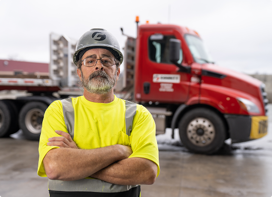 County Materials truck driver standing confidently in front of a red semi-truck.
