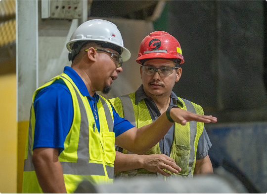 County Materials supervisor discussing work inside a manufacturing facility.